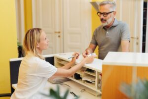 man talking to front desk at dentist’s office 