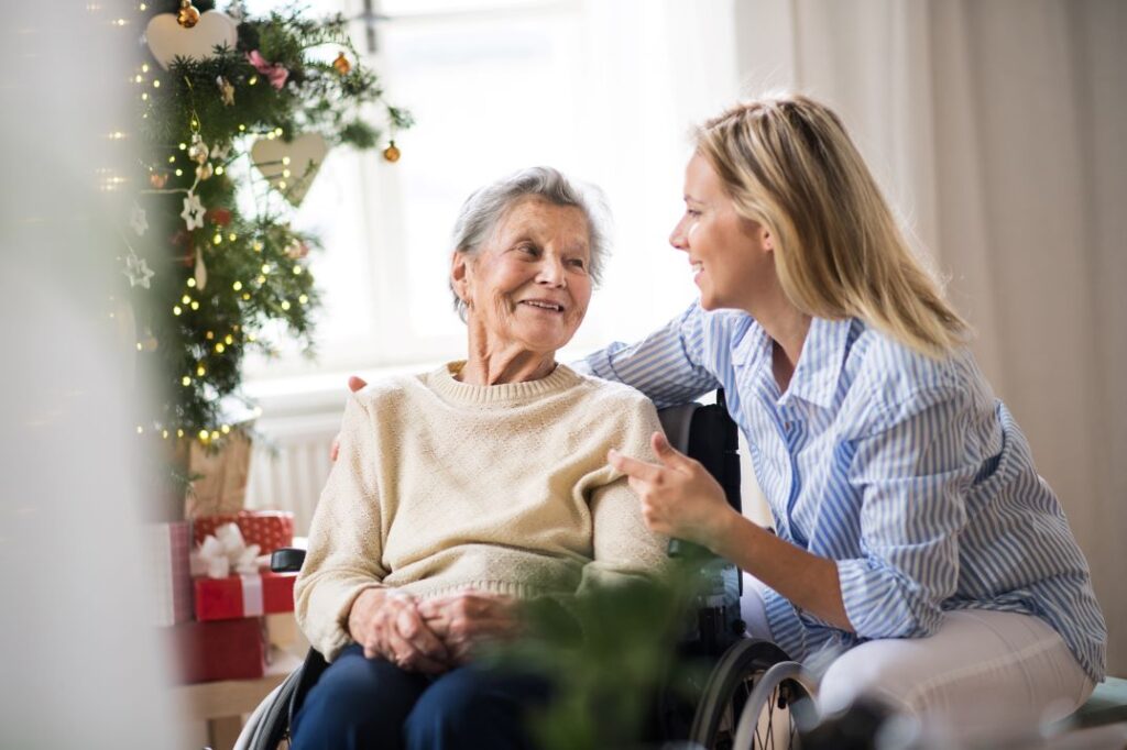 An older woman and younger woman embracing by a Christmas tree